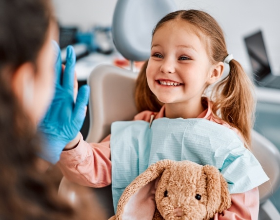 Young girl grinning and giving high five to dental team member
