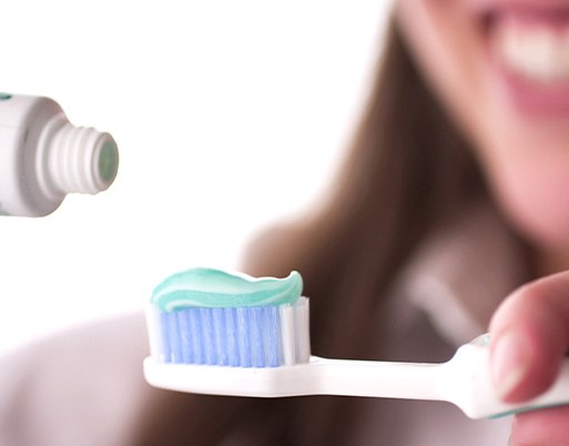 Lady applies toothpaste to brush