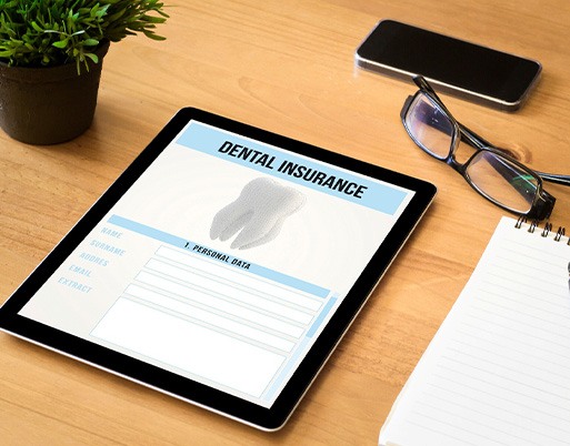 Dental insurance form on tablet next to office supplies