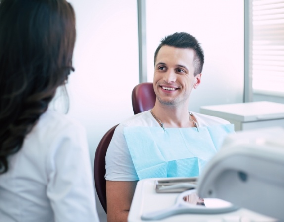 Man in dental chair talking to dental team member