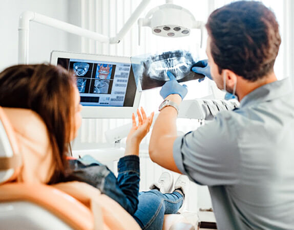Dentist in blue gloves showing X-ray image to patient