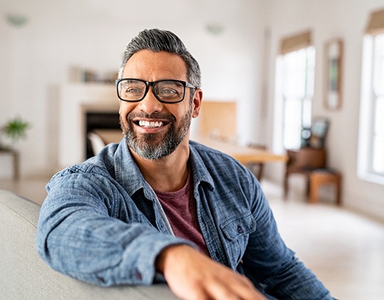 Middle-aged man wearing glasses and smiling happily