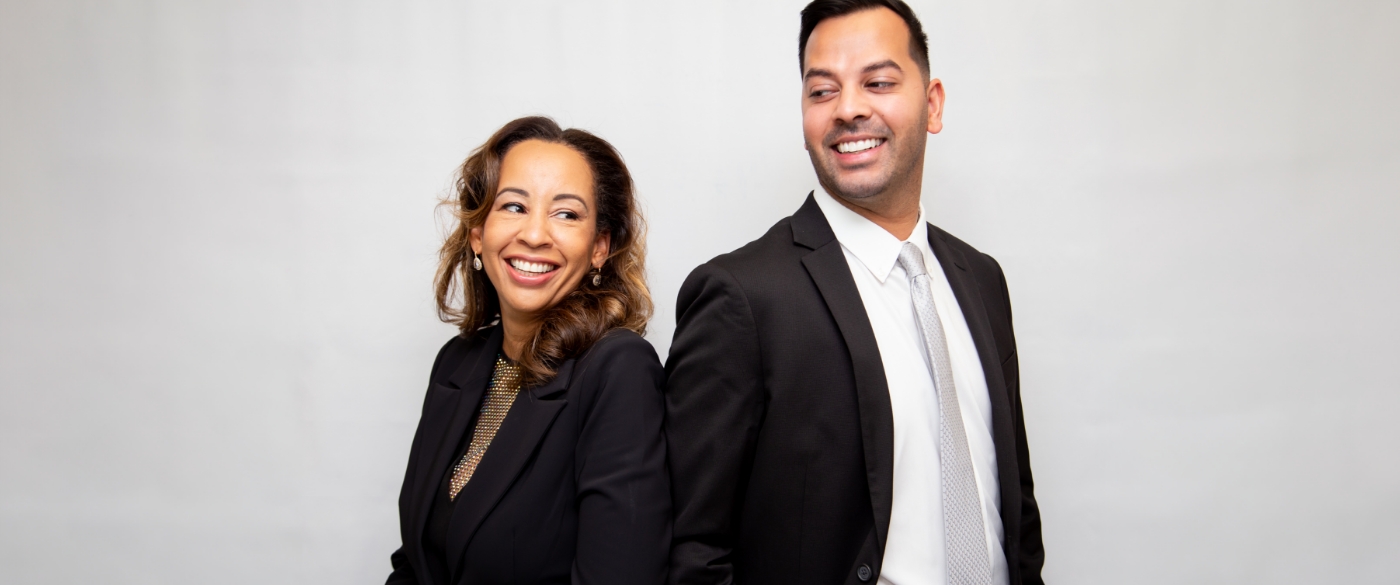 Doctor Gordon Holt and Doctor Shah standing back to back and smiling while turning toward each other