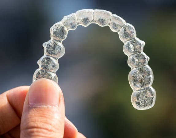 Hand holding an Invisalign clear aligner