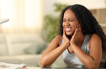 Woman at her desk rubbing her aching ja
