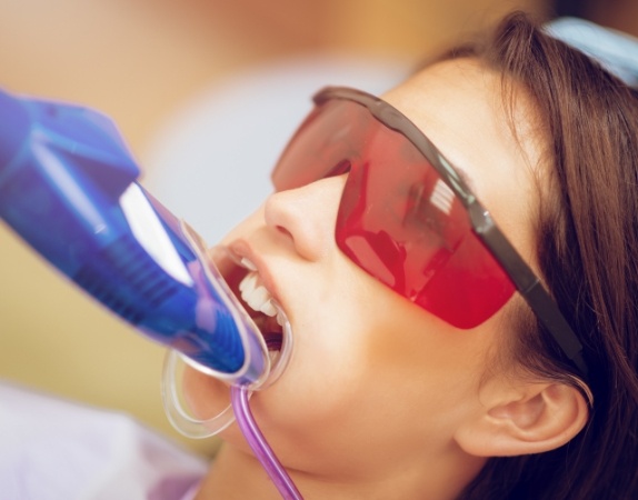 Young woman in dental chair with fluoride trays on her teeth