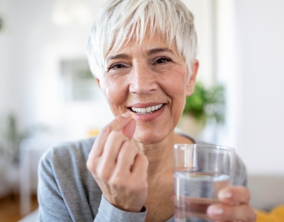 Woman holding pill and glass of water