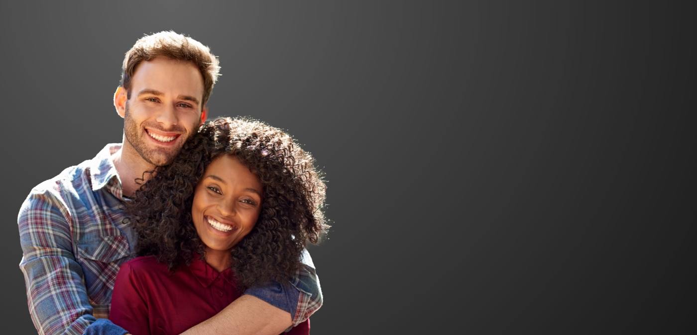 Smiling man hugging a smiling woman from behind