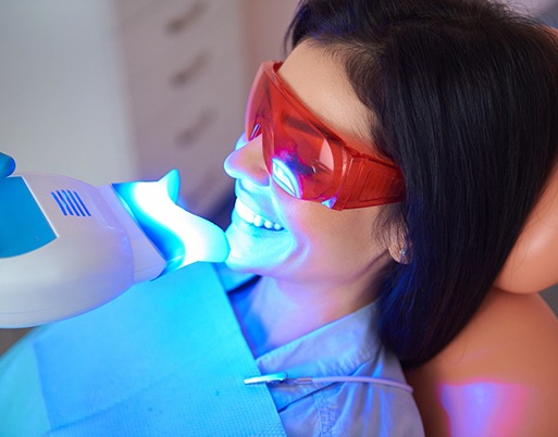 Woman undergoing teeth whitening procedure at dental office