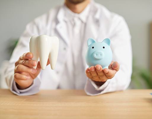 Man in white coat holding large model tooth and small blue piggy bank