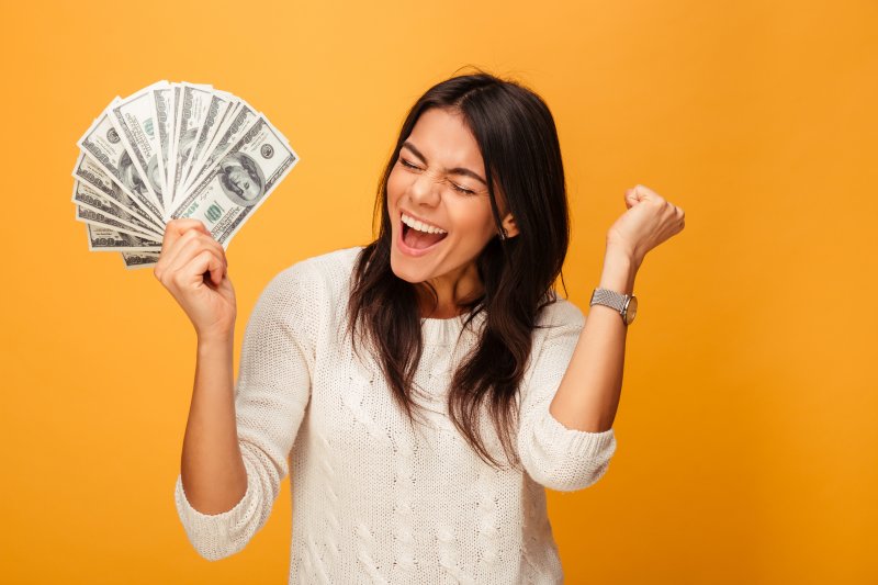 Patient holding up some money to invest in oral health