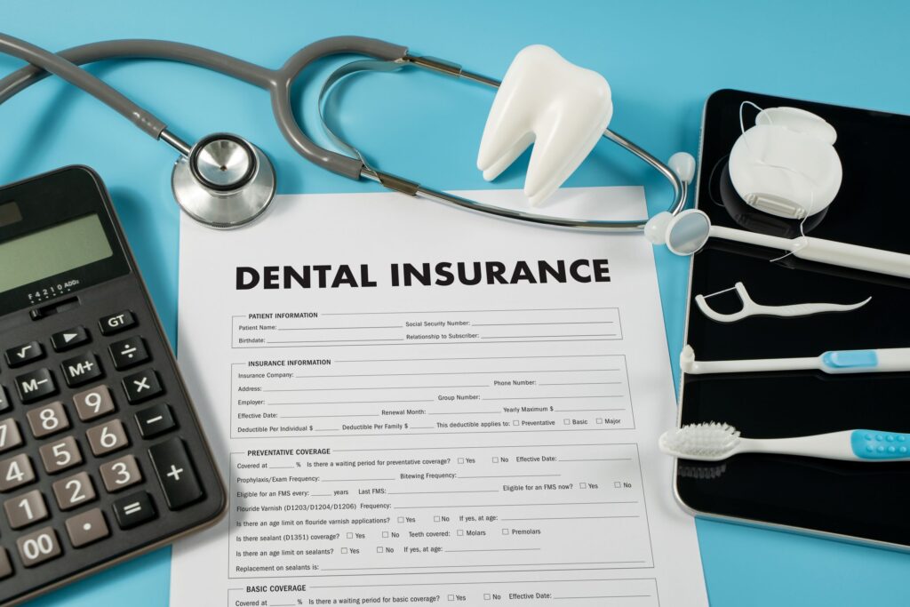Dental insurance form with calculator and dental supplies on light blue surface