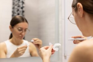 Woman whitening her teeth at home. 